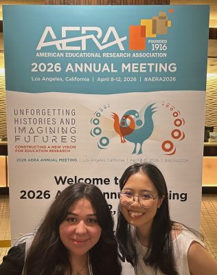 Two undergraduates in front of an AERA 2026 sign