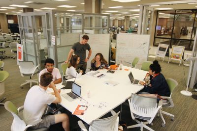 Students work around a table in the blackstone launchpad in bird library