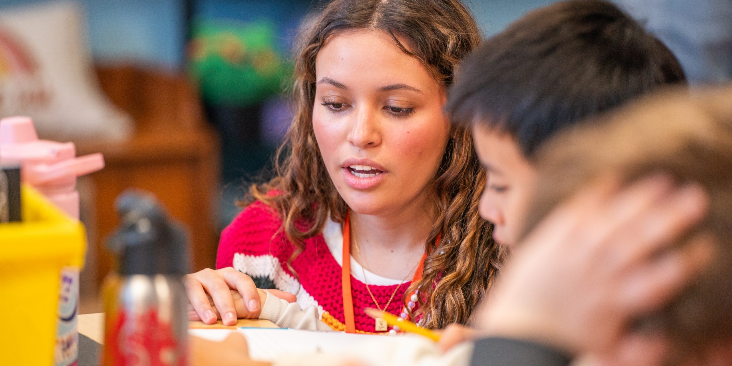 elena perez works with an elementary school student at their desk in a new york city classroom