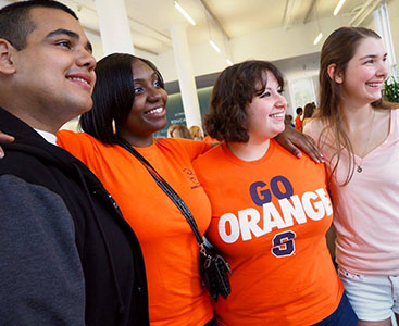 four alumni pose together during a homecoming event, in orange syracuse clothing
