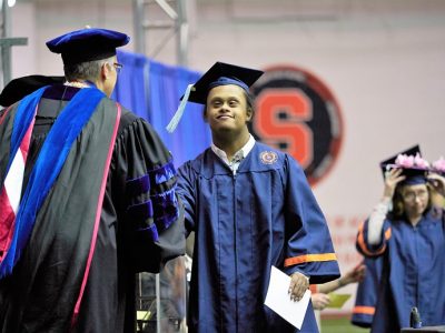 student crossing stage in cap and gown